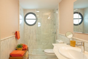 Ein Badezimmer mit Duschkabine, Toilette, Waschbecken mit Spiegel und Handtuchhalter.