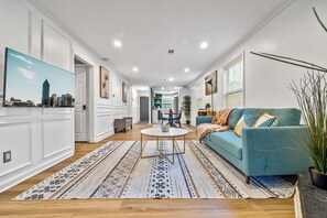 Un soggiorno moderno con un divano blu, un tavolino rotondo e un tappeto decorato.