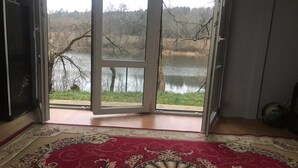 A room with a large window revealing a lake and trees. - Sazava River Cottage With Boating Experience (Týnec nad Sázavou)