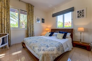 Quarto com uma cama grande, duas luminárias de cabeceira, uma cadeira e uma janela com cortinas.