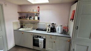 Une cuisine compacte équipée d’un lave-vaisselle, d’un four et d’une machine à café posée sur le plan de travail.
