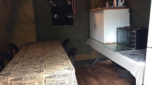 Une pièce compacte comprenant une table à manger, des chaises, un réfrigérateur, un four à micro-ondes et un étagère suspendue.