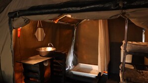 Une tente équipée d’un évier en métal, d’une table et d’un banc.