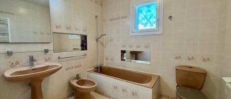 A bathroom with a sink, toilet, bidet, and bathtub.