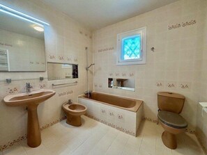 Et badeværelse med vask, toilet, bidet og badekar.