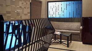 Un hall d’entrée moderne avec un mur orné d’un motif géométrique, un canapé, une petite table et un réfrigérateur.