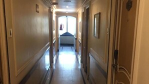 Un long couloir étroit, doté d’un sol carrelé et de portes de part et d’autre.