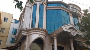 Un immeuble à plusieurs étages de style architectural classique, doté de grandes fenêtres et d’une entrée imposante ornée de colonnes.