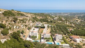 An aerial view of a residential area with houses, a swimming pool, and a view of the sea. - Peaceful Villa with Private Pool, BBQ & Kids Area (Rethymno)