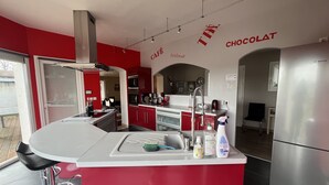 Una cocina moderna con armarios rojo y blanco, electrodomésticos de acero inoxidable y una barra con taburetes.
