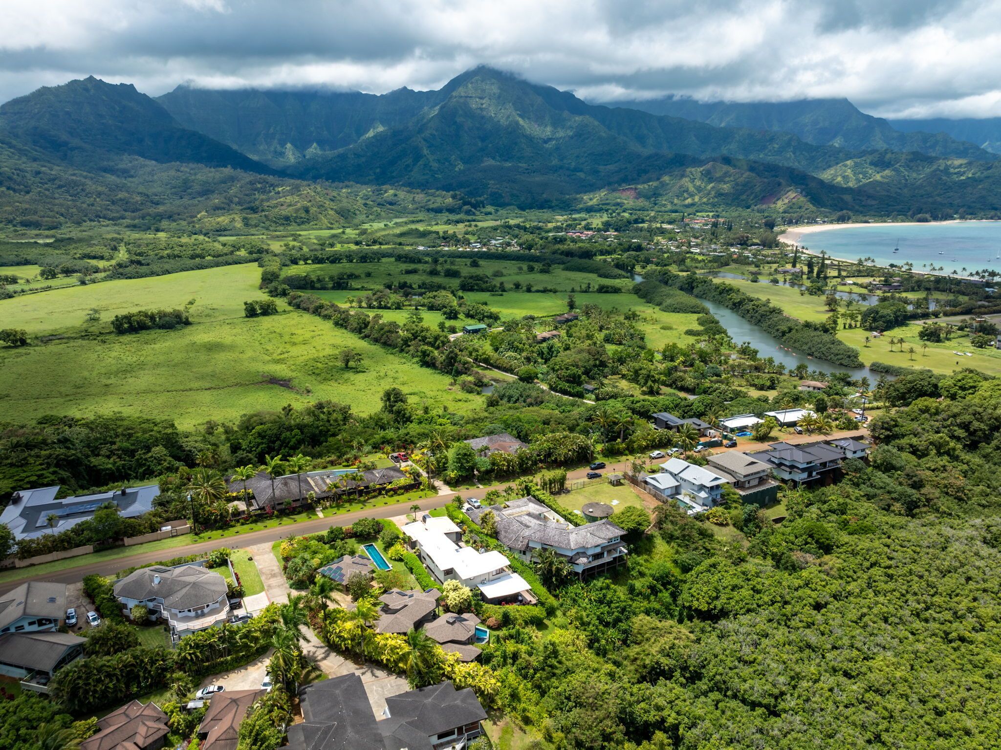 A residential area with houses, a river, and mountains in the background.