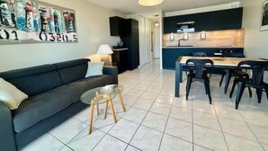 A modern living room with a sofa, a glass coffee table, and a dining area with a table and chairs. - Quiberon - 2 rooms apartment - 42m² - sea view (QUIBERON)