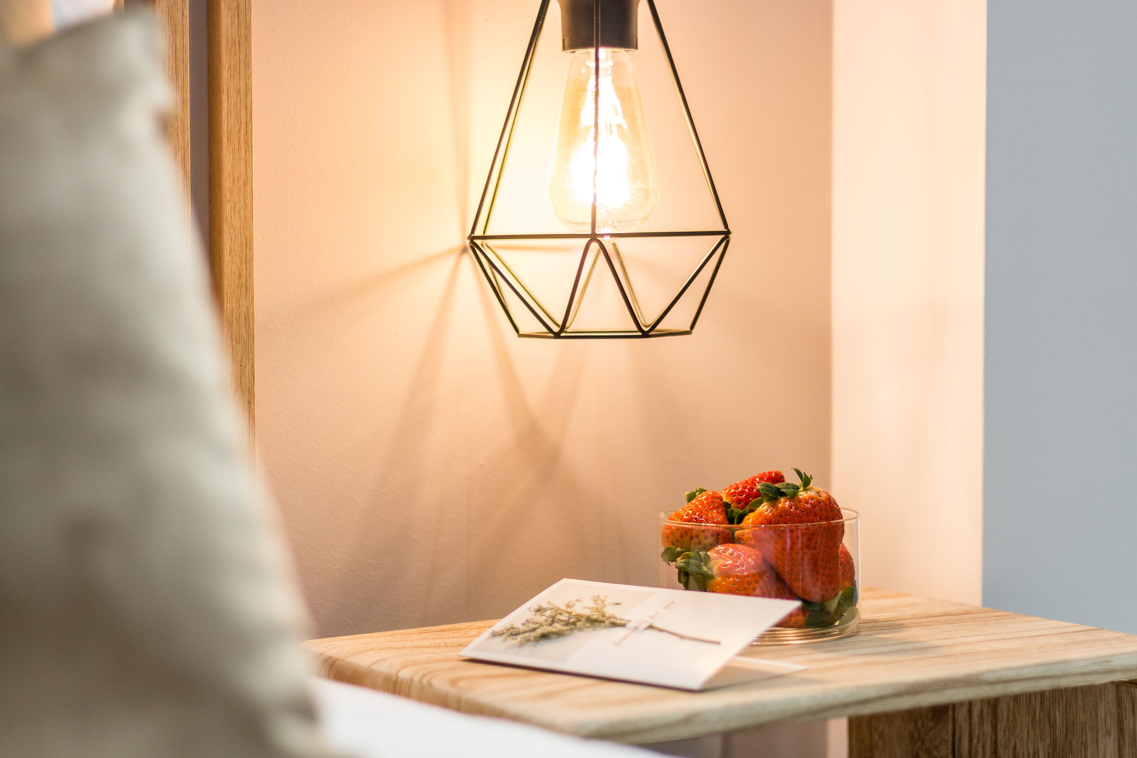 A wooden table with a glass of strawberries and a notepad.