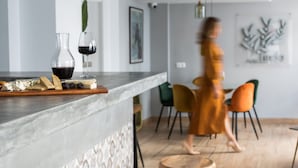 A modern kitchen with a marble countertop, a wine glass, and a cheese board.