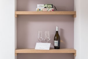 A wooden shelf with a wine bottle and two glasses, a thank you card, and a box labeled "tree houses".