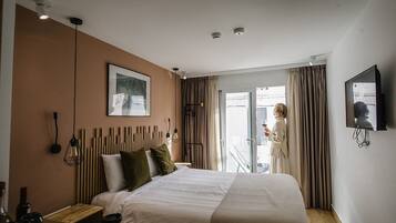 Habitación de hotel con cama, mesita de noche y televisión montada en la pared.
