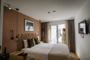 A hotel room with a bed, bedside table, and a TV mounted on the wall.