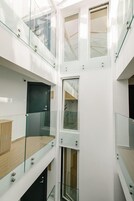 Een meerlaags interieur met glazen balustrades en witte muren, met een centrale trap en een deur met een handgreep.