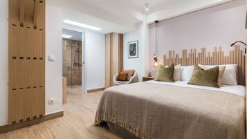Een moderne slaapkamer met een groot bed, houten lambrisering, een stoel en een douchegedeelte.