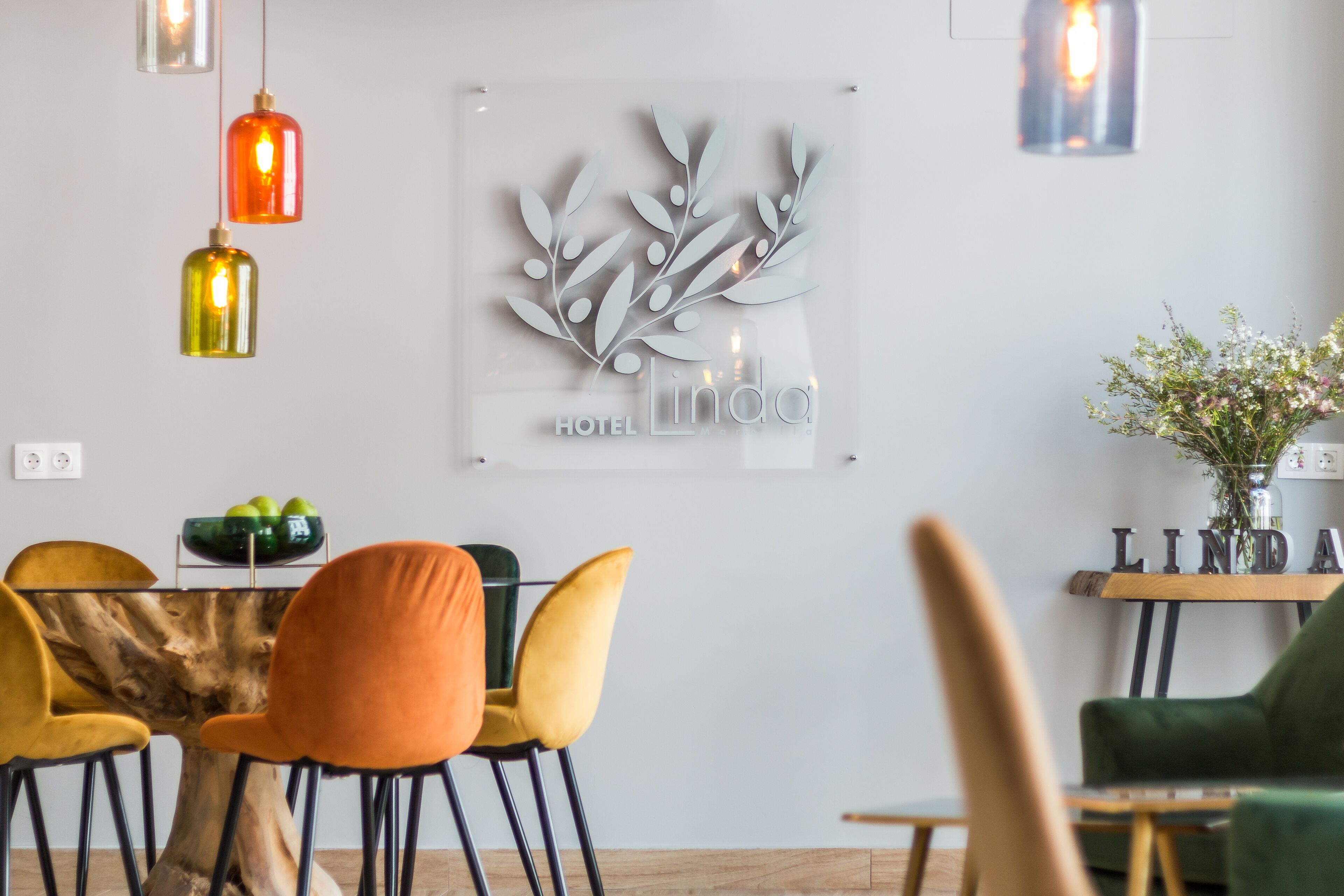 Un comedor moderno con una mesa de madera, sillas naranja y amarillas, y un elemento decorativo en la pared.