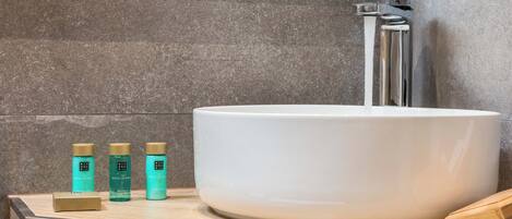 A bathroom with a white sink, a mirror, and three bottles of body lotion on the countertop.