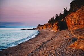 Una playa rocosa con vistas al océano y un acantilado cubierto de bosque.