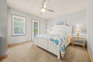 A bedroom with a bed, two bedside tables, a ceiling fan, and a window with blinds. - Out of the Blue 8 Bedroom Home With Private Pool (Corolla)
