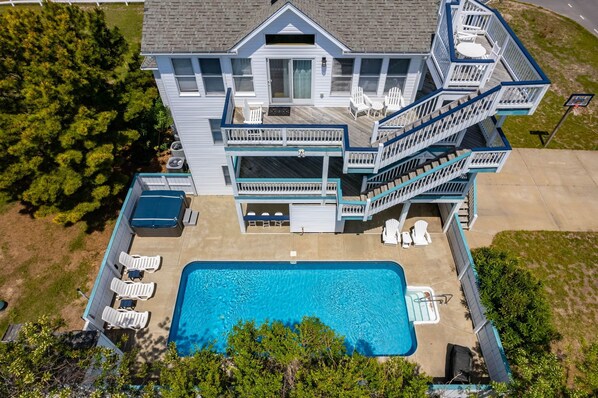 A two-story house with a swimming pool, outdoor seating, and a deck. - Out of the Blue 8 Bedroom Home With Private Pool (Corolla)