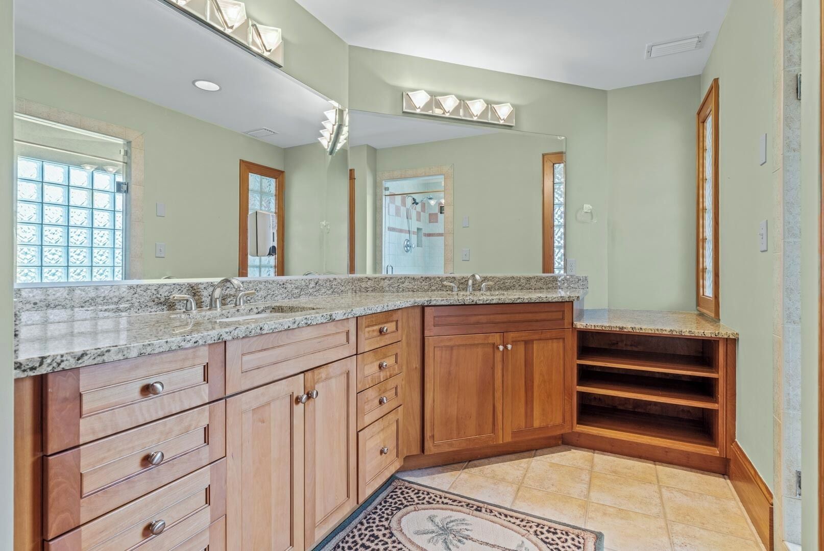 Une salle de bain spacieuse avec un comptoir en granit, des armoires en bois et un grand miroir.