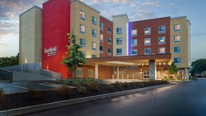 Un hotel de varios pisos con una fachada roja destacada, numerosas ventanas y un área de entrada bien iluminada.