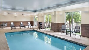 Una piscina interior con sillones de descanso y vistas a árboles a través de amplios ventanales.