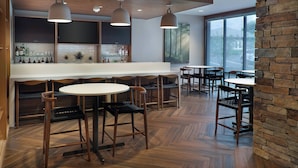 Un bar moderno con suelo de madera, una barra blanca y diversas opciones de asientos.