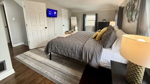 Un dormitorio con cama, televisión, escritorio y lámpara.