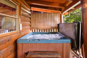 Una bañera de hidromasaje de madera con un muelle de madera y una valla de madera al fondo.