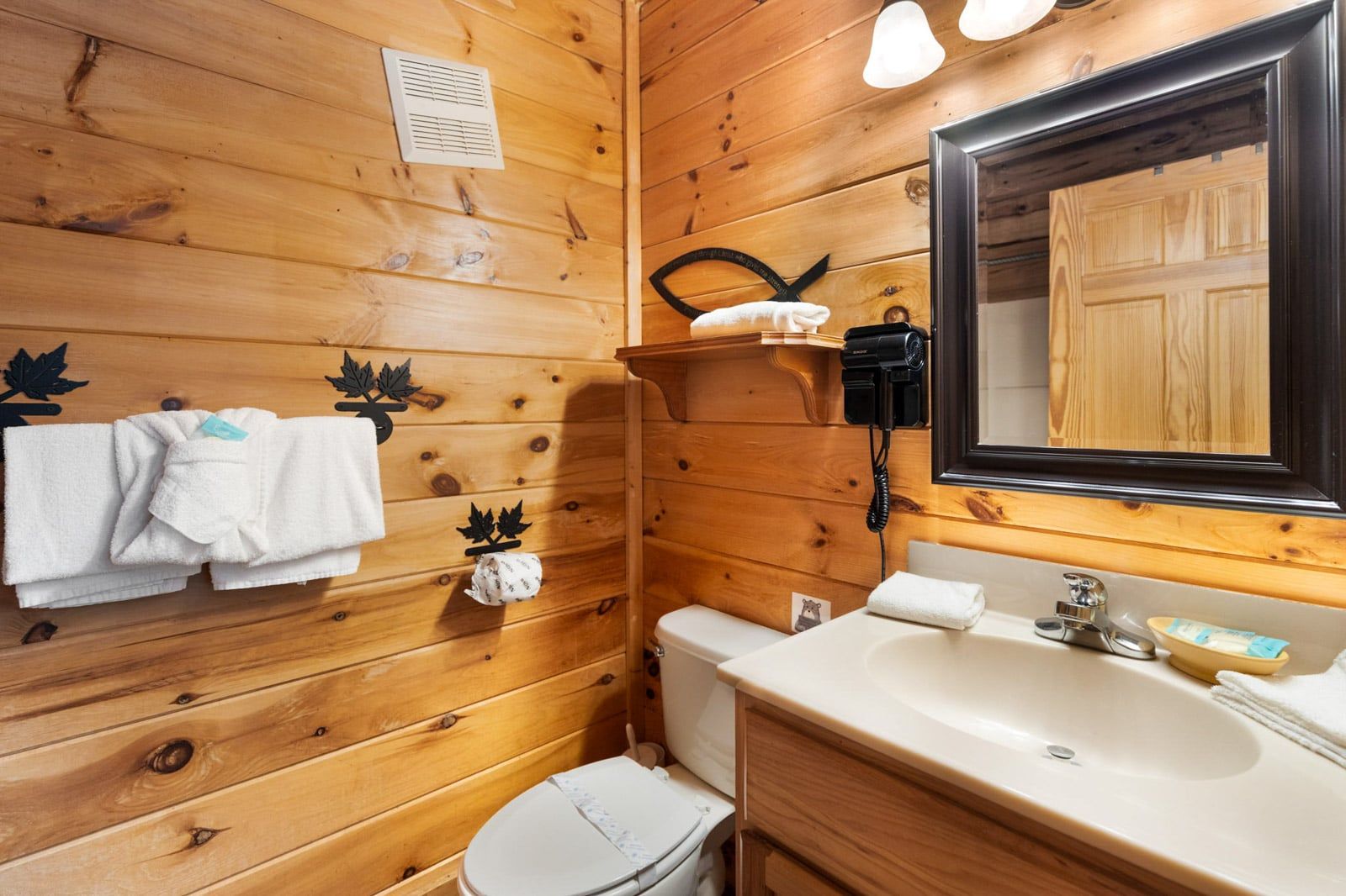 Ein Badezimmer mit Holzwandverkleidung, Toilette, Waschbecken und Spiegel.