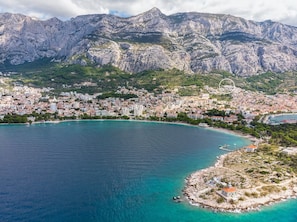 Un pueblo costero con una bahía, edificios y montañas al fondo.
