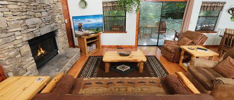 Una sala de estar acogedora con chimenea de piedra, asientos confortables y ventanas amplias con vistas al exterior.
