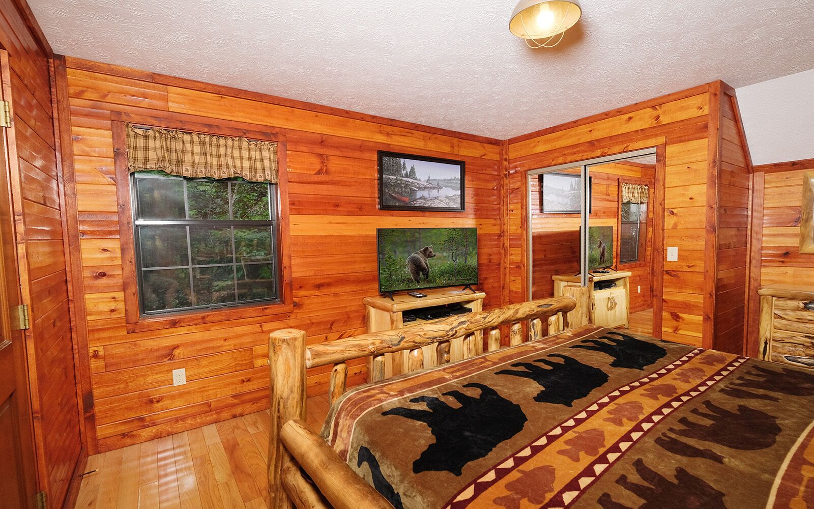A wooden cabin interior with a bed, a television, and a mirror.