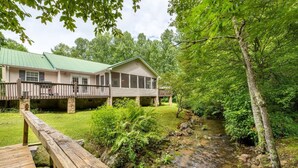 Eine Lodge mit überdachter Veranda und einem Bach im Vordergrund.