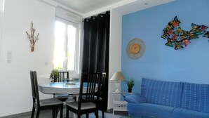 A dining area with a round table, chairs, a glass-top coffee table, and a blue sofa. - The blue house (Fécamp)