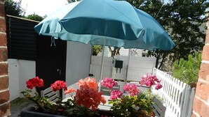 A garden with a blue umbrella, red and pink flowers, and a white picket fence. - The blue house (Fécamp)