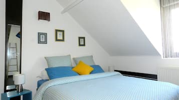 Une chambre à coucher avec un lit, une table de chevet, un miroir et une fenêtre avec des rideaux.