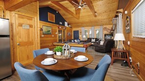 Un intérieur de chalet chaleureux comprenant un coin repas, une table de billard et un salon.