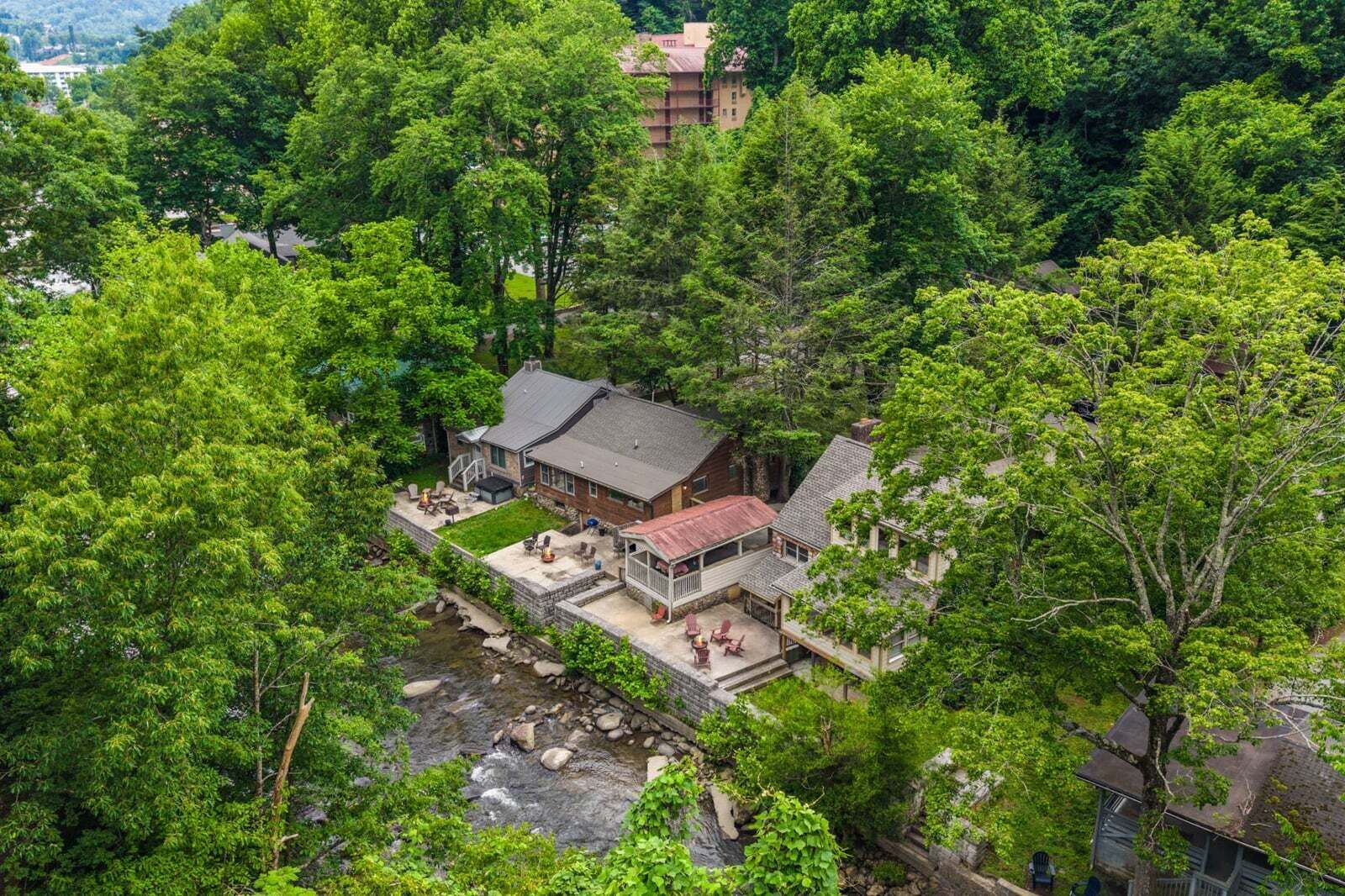 A house surrounded by dense trees with a small patio area.