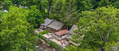 A house surrounded by dense trees with a small patio area.