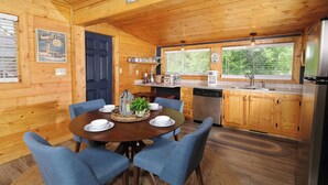 L’intérieur d’une cabane en bois comprend un coin repas, une cuisine et de grandes fenêtres.