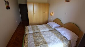 A bedroom with a bed, wooden wardrobe, and a wall-mounted light fixture. - Ideal room Jelka 1 for 2 people on the island of Krk (Malinska)
