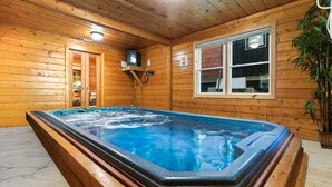 A hot tub in a wooden cabin with a window and a sign indicating no diving.