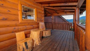 A wooden cabin with a porch featuring a wooden bench and a window. - Oh Yea - Pet Friendly, Hot Tub & Games (Sevierville)
