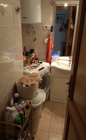 A small laundry room with a washing machine, a sink, and a basket filled with laundry. - Inviting 2-bed Apartment in Moscenicka Draga (Moscenicka Draga)